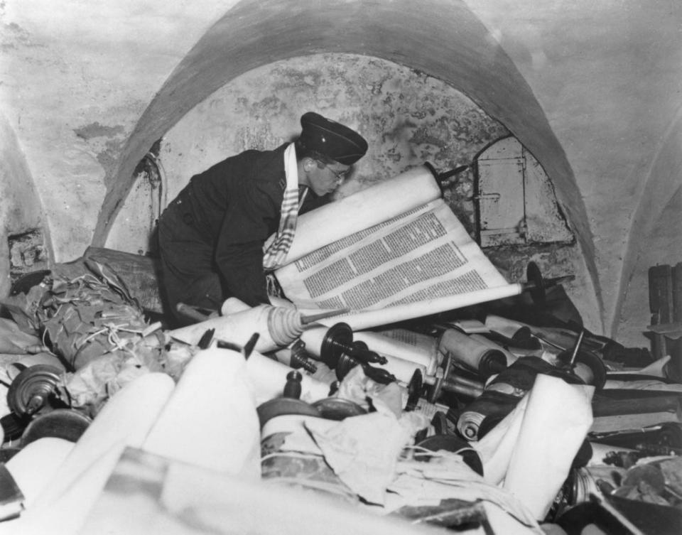 US Army chaplain Samuel Blinder examines one of hundreds of Jewish Sefer Torah scrolls, stolen from all over Europe by Nazi forces, and stored in the cellar of the Kaiser Wilhelm Institute of Anthropology, Human Heredity, and Eugenics (KWI-A) in Frankfurt, Germany, 6th July 1945 (Getty Images)