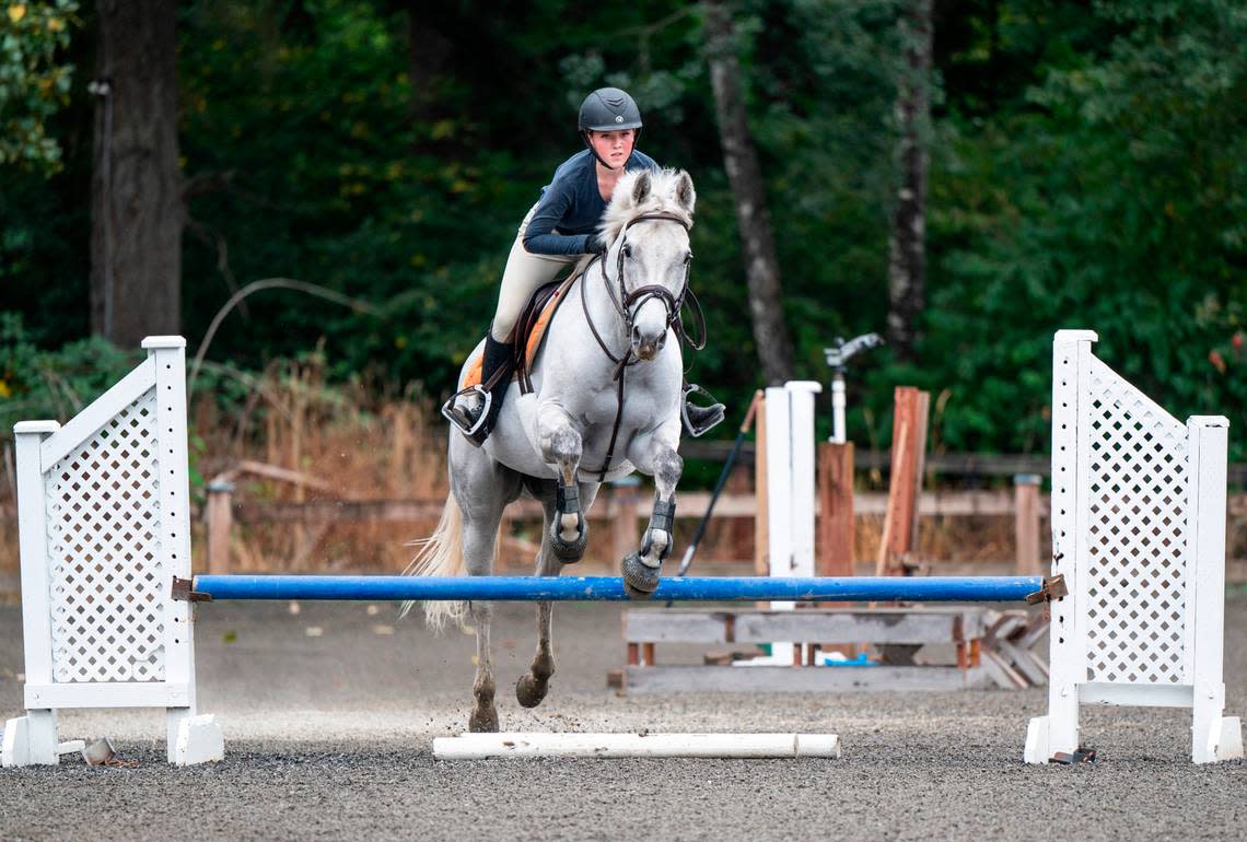 Emerald Ridge High School sophomore Emily Bingham practices jumps with her horse, Q It Up, at Signature West Farms LLC in Spanaway, Wash. on Sept. 22, 2022. Bingham was nominated by the Washington State Hunter Jumper Association for the Marshall & Sterling Insurance/USHJA National Championships, a competition for riders in the country to earn national titles.