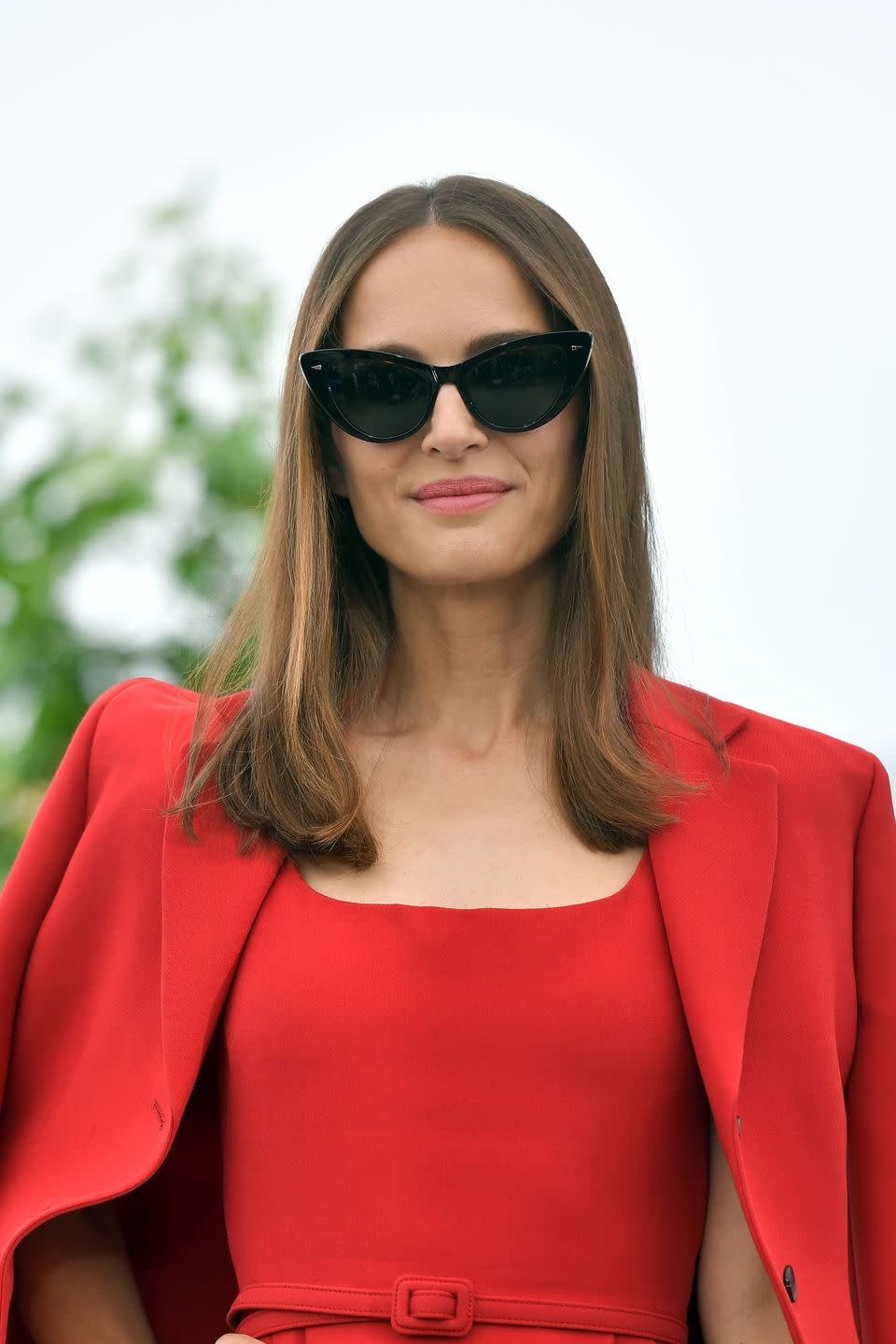 natalie portman in cannes 2023, wearing a red dress with a red jacket over it, and black shades