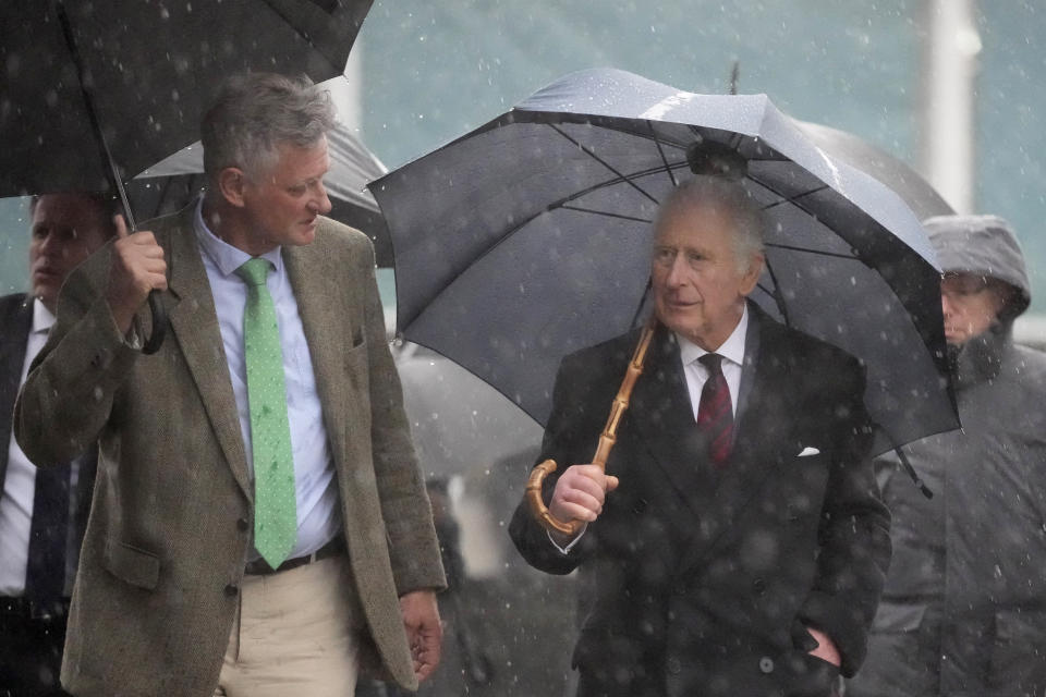 Britain's King Charles III, center, visits the Brodowin organic farm during a thunderstorm, in the village of Brodowin, about 80 kilometers, 50 miles, northeast of Berlin, Thursday, March 30, 2023. King Charles III arrived Wednesday for a three-day official visit to Germany. (AP Photo/Matthias Schrader, Pool)