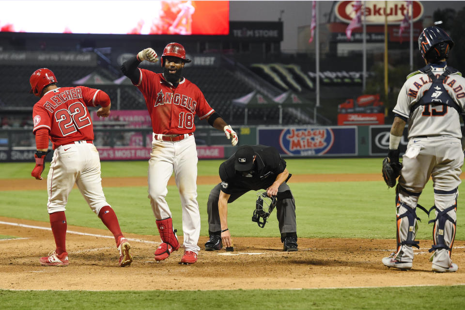 Los Angeles Angels' Brian Goodwin, second from left, is congratulated by David Fletcher, left, as Houston Astros catcher Martin Maldonado, right, stands by and home plate umpire Cory Blaser wipes the plate after Goodwin hit a two-run home run during the fourth inning of a baseball game Friday, July 31, 2020, in Anaheim, Calif. (AP Photo/Mark J. Terrill)