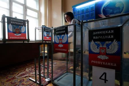 A member of a local electoral commission takes part in the preparations for the upcoming election, with stickers displaying symbols of the self-proclaimed Donetsk People's Republic seen on ballot boxes, at a polling station in Donetsk, eastern Ukraine, October 31, 2014. REUTERS/Maxim Zmeyev