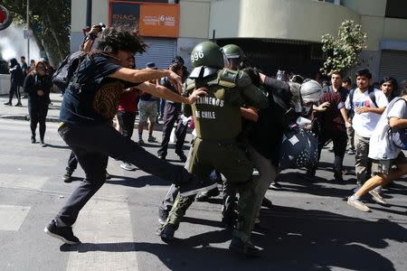 Un policía antidisturbios trata de detener a un manifestante en una protesta por cambios al sistema de educación en Santiago de Chile. 11 de abril de 2017. Miles de estudiantes chilenos marcharon el martes en protesta por lo que califican como una crisis en el sistema educativo, en momentos en que el Congreso prevé iniciar la discusión de una reforma a la educación superior. REUTERS/Ivan Alvarado