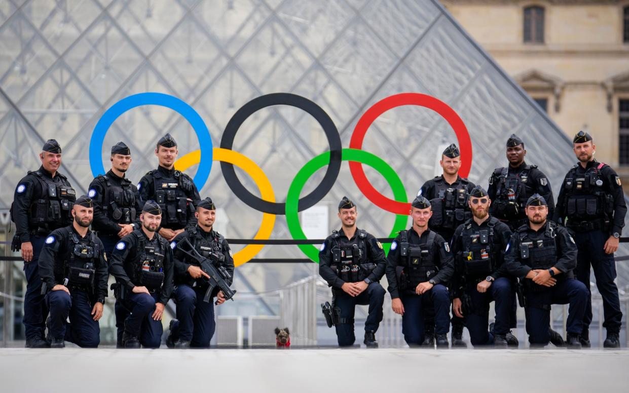 French police pose for a group photo outside the Louvre during the opening ceremony of the 2024 Summer Olympics