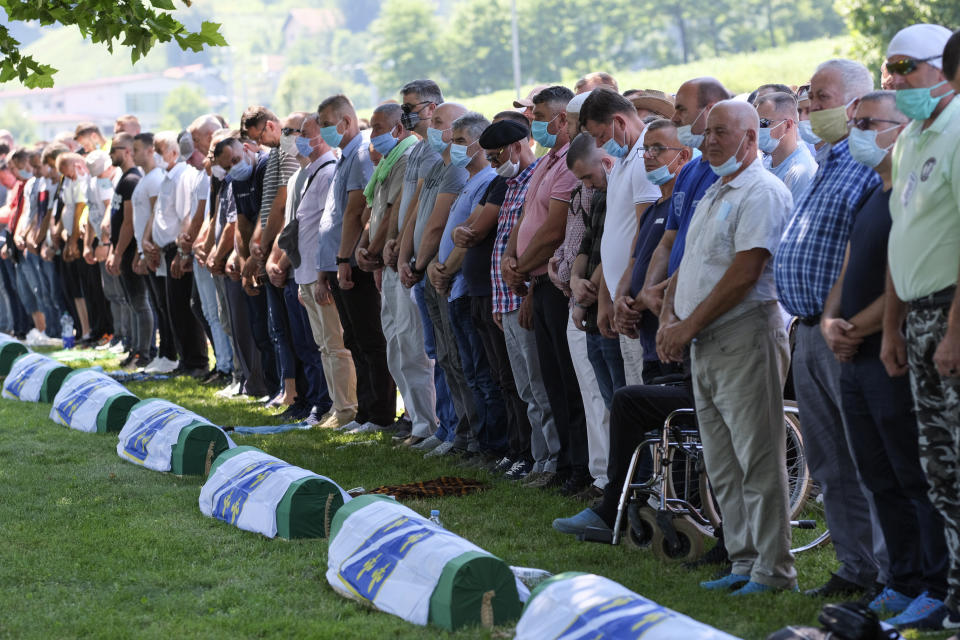 Bosnian pray by the coffins of the victims during the burrial in Potocari, near Srebrenica, Bosnia, Saturday, July 11, 2020. Mourners converged on the eastern Bosnian town of Srebrenica for the 25th anniversary of the country's worst carnage during the 1992-95 war and the only crime in Europe since World War II that has been declared a genocide. (AP Photo/Kemal Softic)