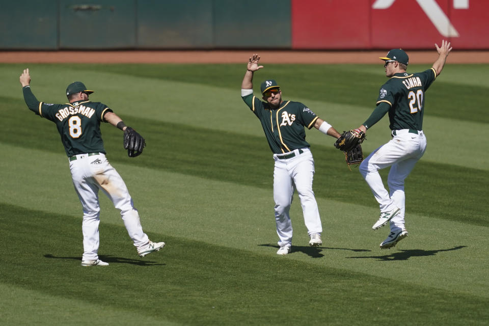 Oakland Athletics' Robbie Grossman, left, celebrates with Ramon Laureano and Mark Canha, right, after the Athletics defeated the Los Angeles Angels 6-4 in a baseball game in Oakland, Calif., Sunday, July 26, 2020. (AP Photo/Jeff Chiu)