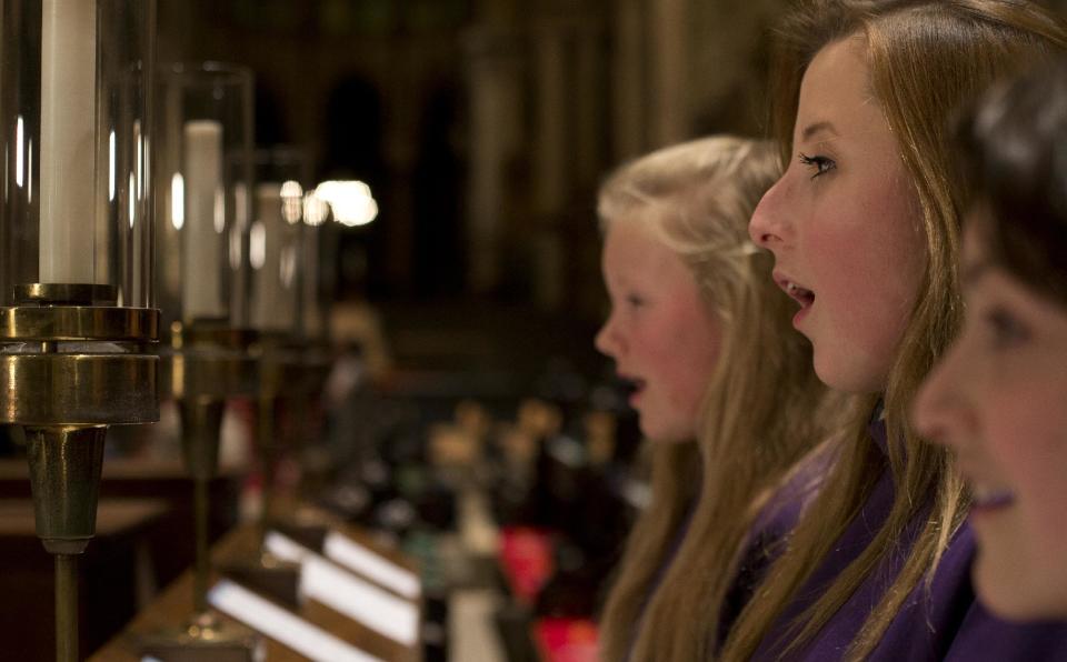In this Wednesday, Jan. 22 2014 photo, choristers Poppy Braddy, centre, Chloe Chawner, right, and Abby Cox sing during an interview with the Associated Press in Canterbury Cathedral, Canterbury, England, as the first all female choir at the cathedral rehearses prior to their debut on Jan. 25. The pure, high voices of the choir soar toward the vaulted ceiling of Canterbury Cathedral as they have for more than 1,000 years. Just one thing is different - these young choristers in their purple cassocks are girls, and their public debut at Evensong on Saturday will end centuries of all-male tradition. Canterbury is not the first British cathedral to set up a girls' choir, but as mother church of the 80 million-strong Anglican Communion - one struggling with the role of women in its ranks - its move has special resonance. (AP Photo/Alastair Grant)