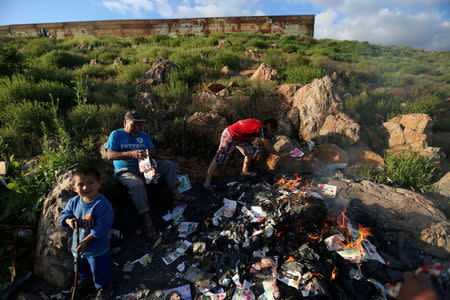 A family burns trash near a section of the border fence separating Mexico and the United States, on the outskirts of Tijuana, Mexico. REUTERS/Edgard Garrido