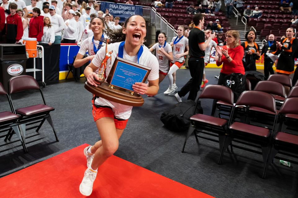 York Suburban senior Janay Rissmiller runs with the trophy to get to the student section after the Trojans won the District 3 Class 5A girls' basketball championship against Northern York at the Giant Center on March 1, 2024, in Hershey. The Trojans won in overtime, 37-35.