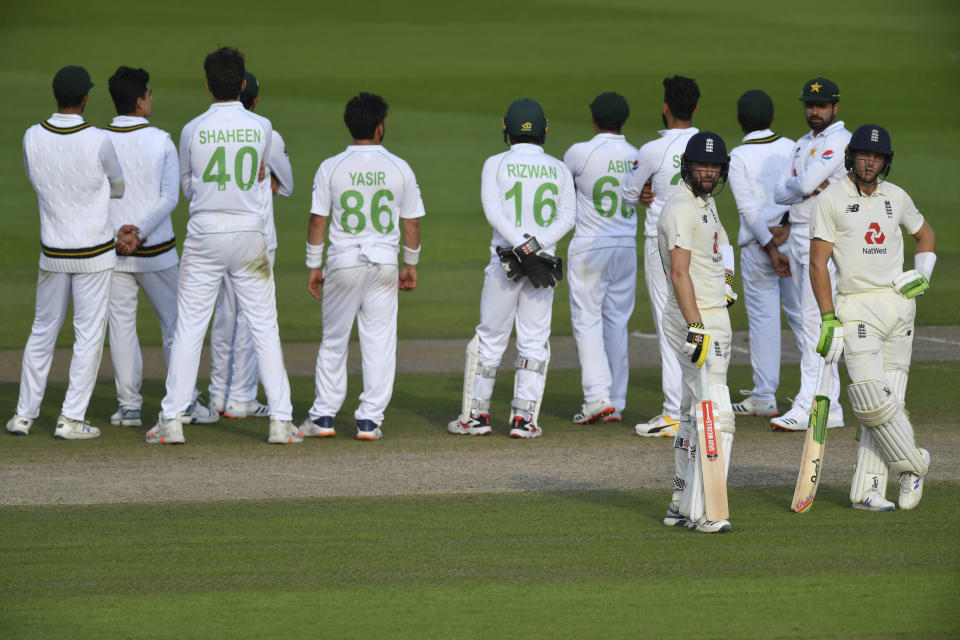 England's Jos Buttler, right, waits for the decision after asking for a review during the fourth day of the first cricket Test match between England and Pakistan at Old Trafford in Manchester, England, Saturday, Aug. 8, 2020. (Dan Mullan/Pool via AP)