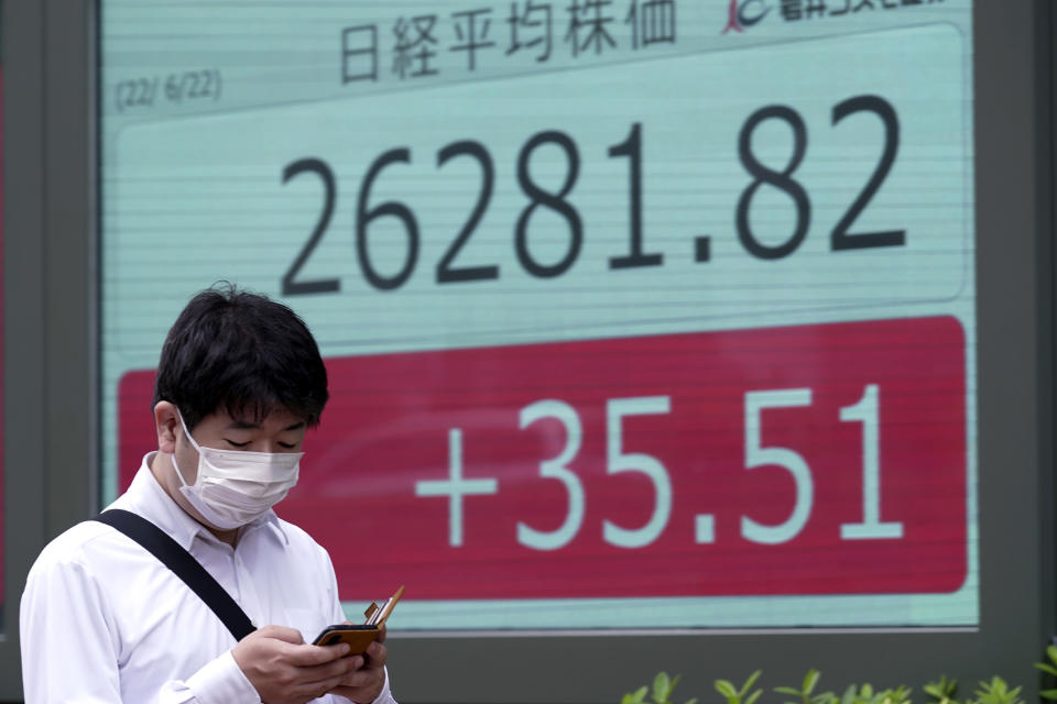 A man wearing a protective mask walks in front of an electronic stock board showing Japan's Nikkei 225 index at a securities firm Wednesday, June 22, 2022, in Tokyo. Asian shares were mostly lower Wednesday as markets shrugged off a Wall Street rally and awaited congressional testimony by Federal Reserve Chair Jerome Powell. (AP Photo/Eugene Hoshiko)