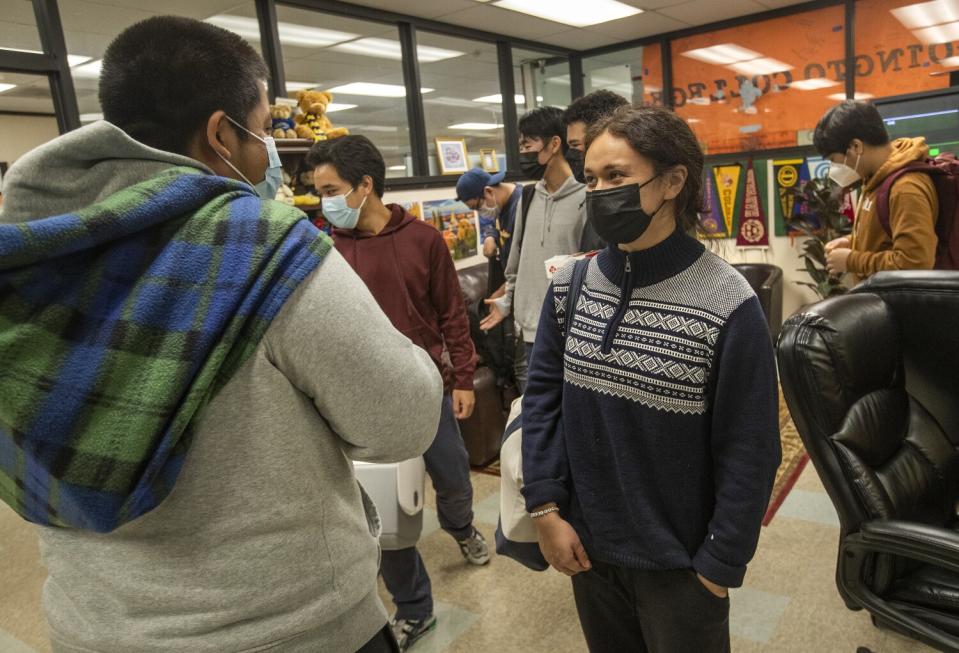 Kevin Hernandez talks to Emily Cruz inside the College Center while other students walk behind them.