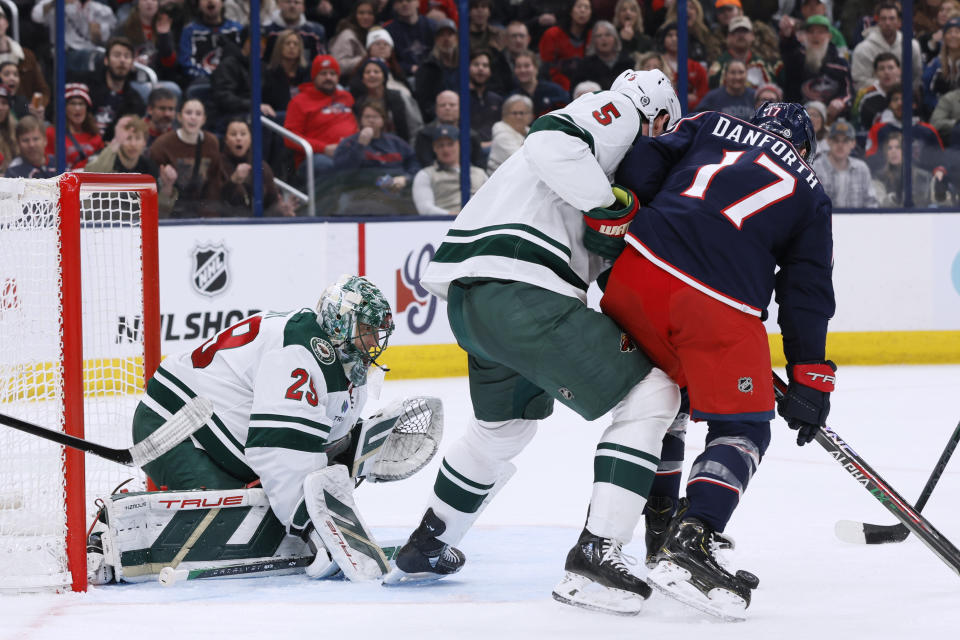 Minnesota Wild's Marc-Andre Fleury, left, protects the net as Jake Middleton, center, and Columbus Blue Jackets' Justin Danforth vie for the puck during the second period of an NHL hockey game Saturday, Jan. 6, 2024, in Columbus, Ohio. (AP Photo/Jay LaPrete)