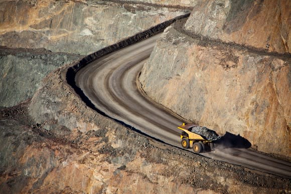 A bird's eye view of a giant earth hauler driving up a road at a gold mine.