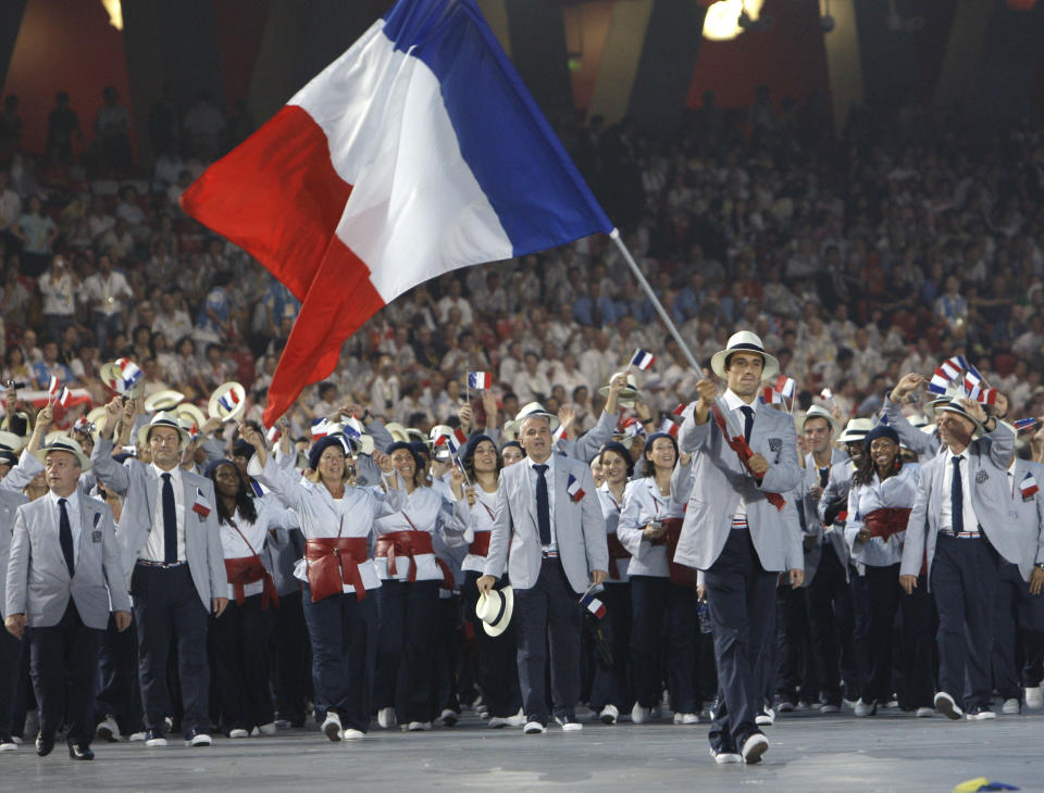 FILE - Tony Estanguet carries the flag of France during the opening ceremonies for the Beijing 2008 Olympics in Beijing, Friday, Aug. 8, 2008. Estanguet who won gold medals for canoeing in the 2000, 2004 and 2012 Olympic Games is now the face and chief organizer of the 2024 Paris Games. In a wide-ranging interview with The Associated Press, Estanguet talks about the two French police probes into Olympic-related contracts, and insists they bear no comparison with corruption and ethics scandals that have dogged the Olympic movement and its flagship money-spinning event for decades. (AP Photo/Kevin Frayer, File)