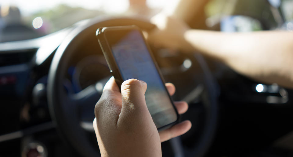 A driver using their mobile phone while driving.