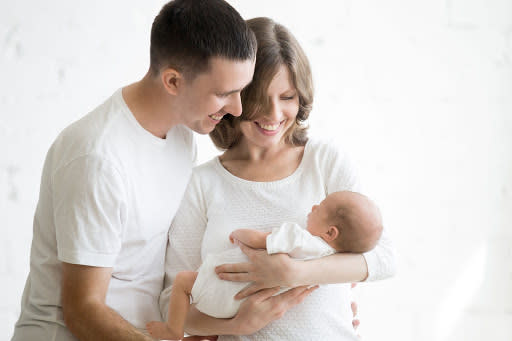 A couple in white t-shirts holding a baby.