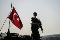 A Turkish police officer stands guard on a tank after the failed military coup that claimed the lives of 240 people on July 15