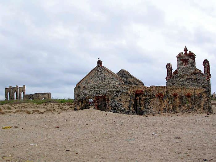 The remains of the church and railway station buildings. A few fishermen have settled here in thatched huts.