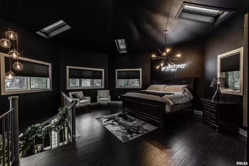 The spiral staircase leads to master bedroom with a neon sign and skylights.