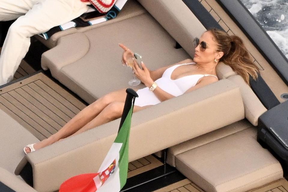 Jennifer Lopez sipping wine and looking at her phone on a boat in Italy. COBRA TEAM / BACKGRID