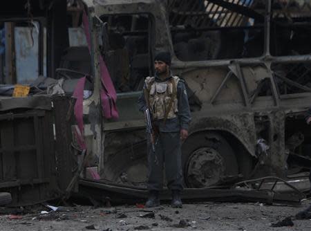 An Afghan policeman stands guard in front of a destroyed bus after the blast in Kabul, November 16, 2013. REUTERS/Mohammad Ismail