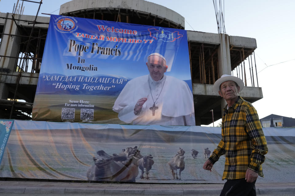 A Mongolian man walks past a banner promoting the visit of Pope Francis near a church in Ulaanbaatar, Mongolia on Monday, Aug. 28, 2023. When Pope Francis travels to Mongolia this week, he will in some ways be completing a mission begun by the 13th century Pope Innocent IV, who dispatched emissaries east to ascertain the intentions of the rapidly expanding Mongol Empire and beseech its leaders to halt the bloodshed and convert. (AP Photo/Ng Han Guan)
