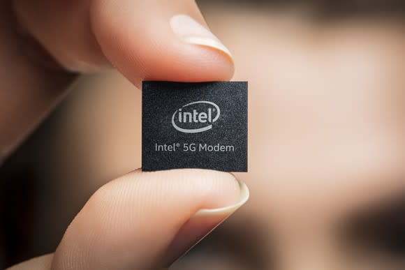 A person holding a chip that says "Intel 5G Modem"