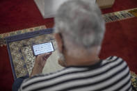 FILE – In this July 15, 2020, file phoro, a worshipper reads verses of the Quran on his mobile phone in a mosque in Rabat, Morocco. Internal company documents from the former Facebook product manager-turned-whistleblower Frances Haugen show that in some of the world's most volatile regions, terrorist content and hate speech proliferate because the company remains short on moderators who speak local languages and understand cultural contexts. (AP Photo/Mosa'ab Elshamy, File)