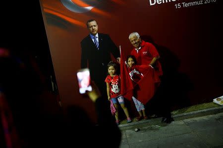A man and his granddaughters pose in front of Turkish President Tayyip Erdogan's picture as they gather with others in solidarity outside Erdogan's palace night after night since the July 15 coup attempt in Ankara, Turkey, July 27, 2016. REUTERS/Umit Bektas