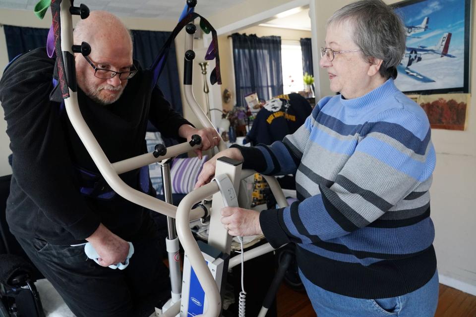 Teresa Brancato, who has been a caregiver for her husband, Joe, since he suffered a stroke in 2011, uses a lift to pick him up out of his wheelchair in the living room of their town of Tonawanda home so he can move into the bathroom.
