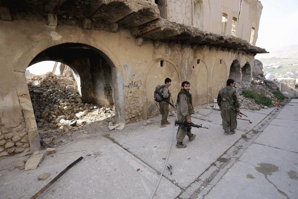 FILE - In this Thursday, Jan. 29, 2015 file photo, fighters of the Turkey-based Kurdish Workers' Party (PKK) walk in the damaged streets of Sinjar, Iraq. Turkey said Wednesday, June 17, 2020, it has airlifted troops for a cross-border ground operation against Kurdish militants in northern Iraq. Turkey regularly carries out air and ground attacks against the outlawed Kurdistan Workers Party, or PKK, which maintains bases in northern Iraq. Wednesday's was the first known airborne land offensive.(AP Photo/Bram Janssen, File)