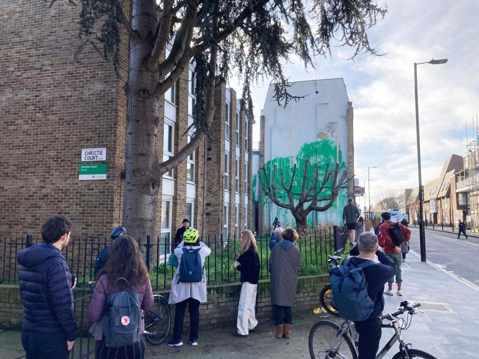 Members of the public look at a new piece of art work, which has appeared on the side of a building on Hornsey Road in Finsbury Park, London, and is suspected of being by street artist Banksy. Picture date: Monday March 18, 2024.