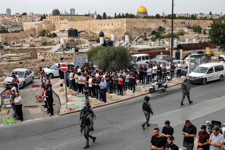 Los guardias fronterizos israelíes pasan junto a los fieles musulmanes durante las oraciones semanales del viernes en el Monte de los Olivos en Jerusalén Este anexada por Israel el 27 de octubre de 2023, antes de las manifestaciones de solidaridad con los palestinos en la Franja de Gaza en medio de los combates en curso entre Israel y el movimiento Hamas