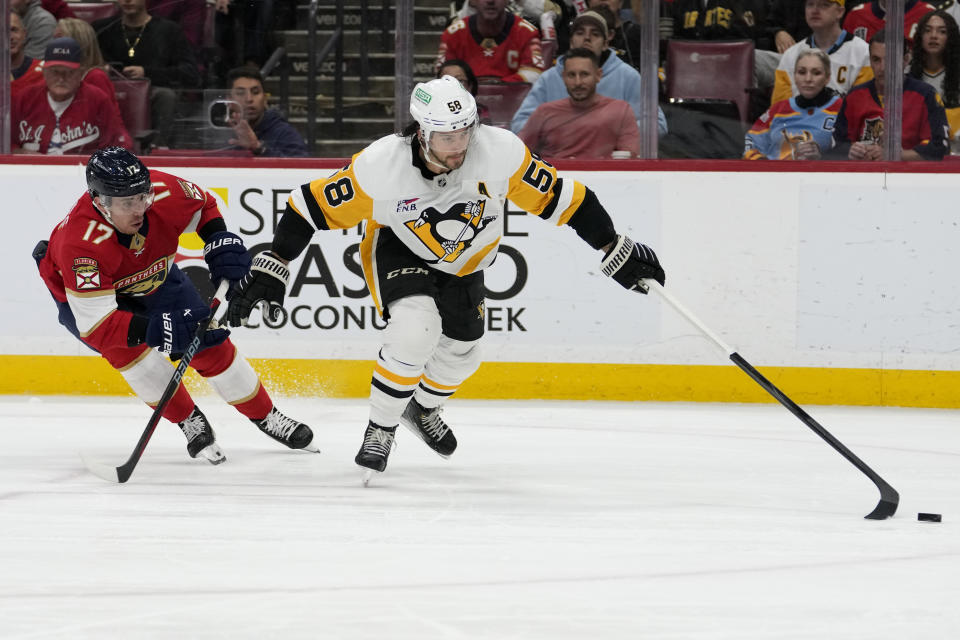 Pittsburgh Penguins defenseman Kris Letang (58) goes for the puck against Florida Panthers center Evan Rodrigues (17) during the second period of an NHL hockey game, Friday, Dec. 8, 2023, in Sunrise, Fla. (AP Photo/Lynne Sladky)