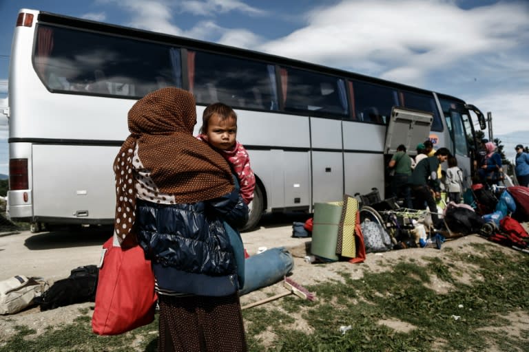 Refugees stand near a bus as they wait to be transferred to a hospitality centre in Greece on May 25, 2016