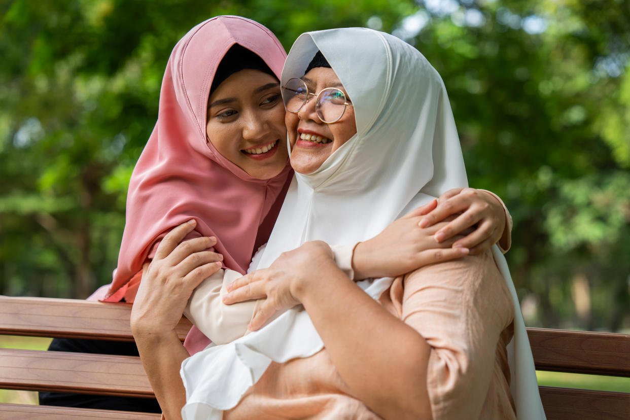 Muslim careful caregiver or nurse taking care of the patient in the hospital park. Happy Muslim mother in hijab hugging daughter. Concept of Savings and Senior Health Insurance, a Happy Family