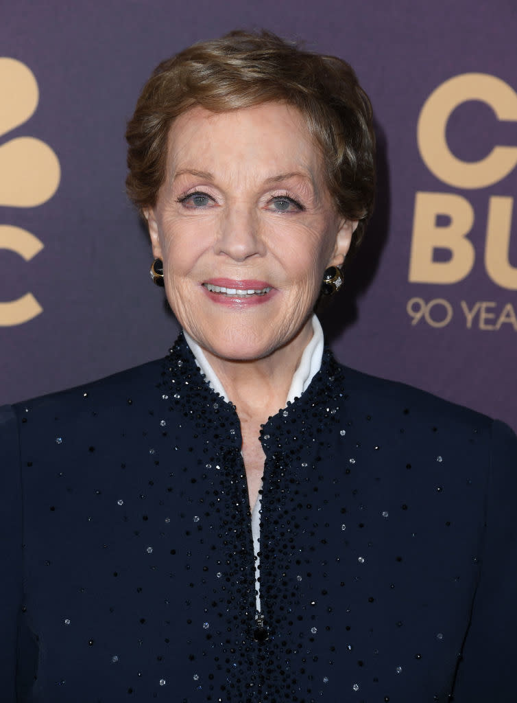 Julie Andrews smiling at event in a dark, embellished outfit