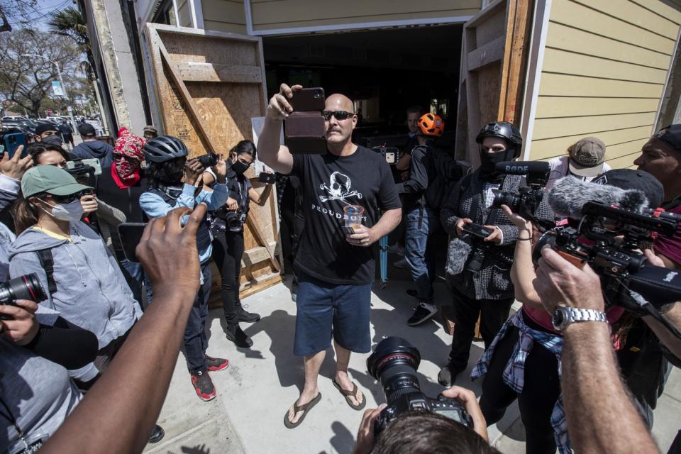 A man takes a video of protesters.