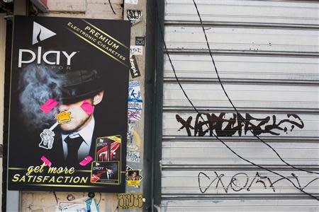 An advertisement for e-cigarettes is covered in stickers and graffiti in New York April 24, 2014. REUTERS/Lucas Jackson