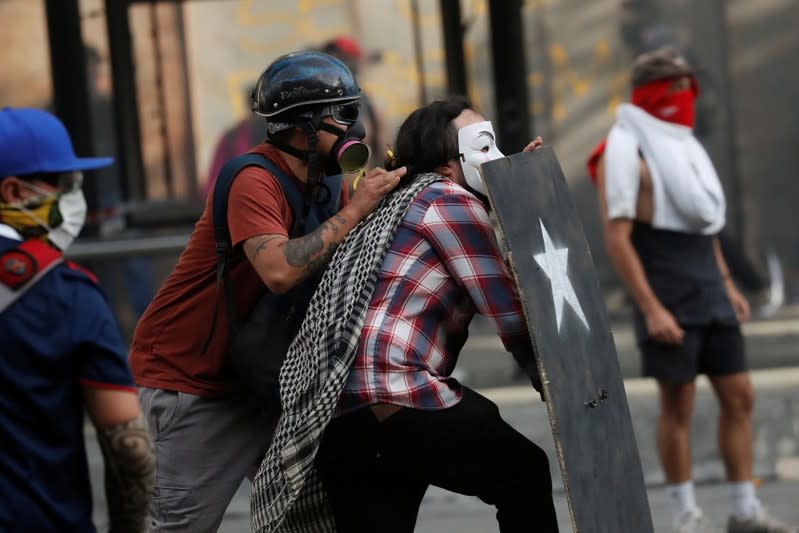 Manifestantes se protegen con un escudo improvisado durante las protestas contra el gobierno en Chile