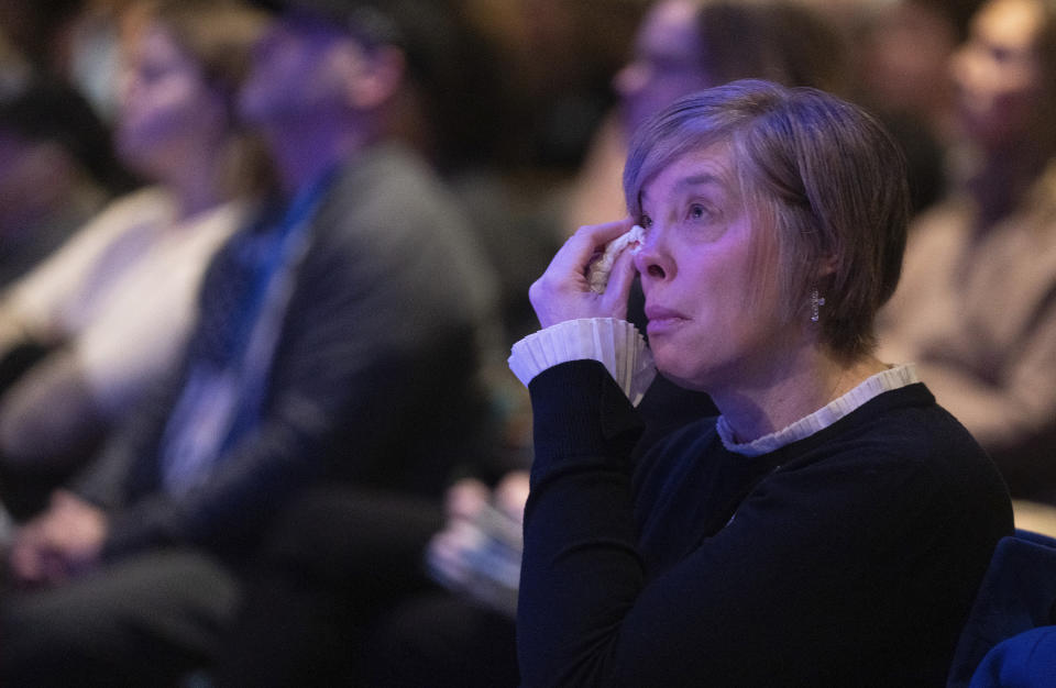 Jessica Olstad wipes tears from her eyes during a live stream of a memorial service for Burnsville police officers Paul Elmstrand, 27, Matthew Ruge, 27, and firefighter-paramedic Adam Finseth, 40, at Prince of Peace in Burnsville, Minn., on Wednesday, Feb. 28, 2024. (Alex Kormann/Star Tribune via AP)