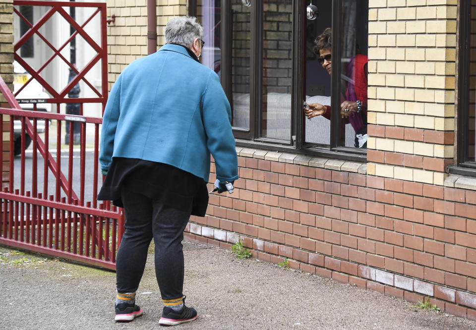 The Rev. April Keech, an Anglican priest, who organizes food deliveries to old and vulnerable people, speaks to a woman after a delivery in London, Saturday, March 28, 2020. Keech and her team of volunteers have spent the past two weeks buying groceries, filling prescriptions and making deliveries to residents in east London who are at risk of serious illness or death from the COVID-19 disease. (AP Photo/Alberto Pezzali)