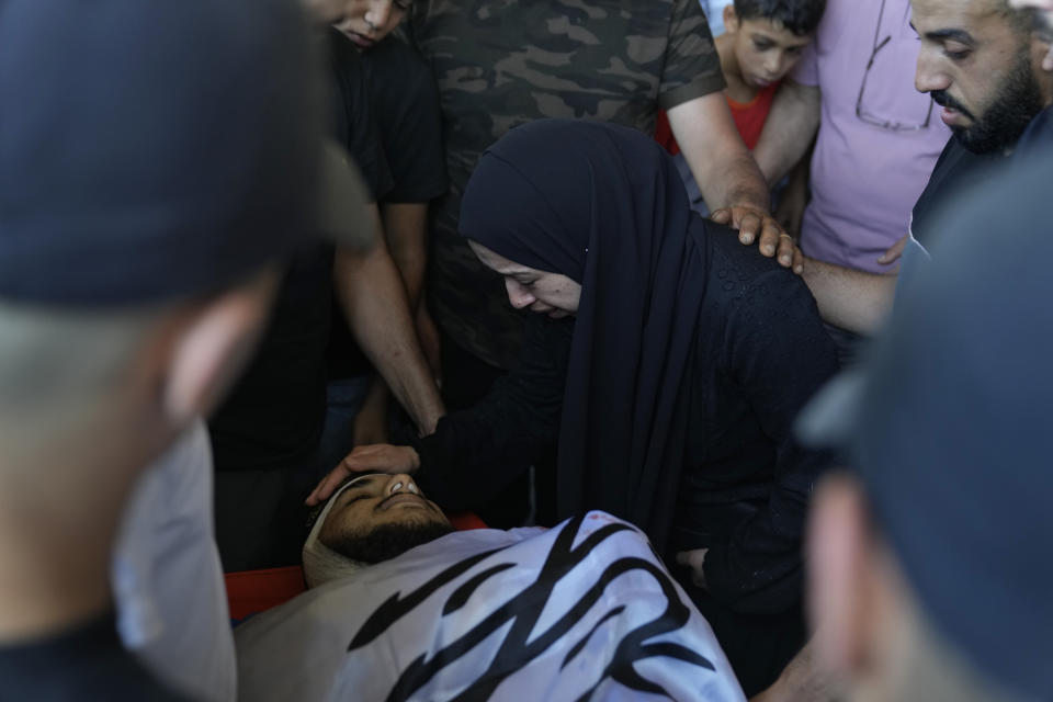 Mourners take a last look at the body of Yazeed Shafea, 22, wrapped with an Islamic Jihad flag, who was one of four Palestinians killed by an Israeli airstrike late Tuesday, during their funeral in the West Bank refugee camp of Nur Shams, near Tulkarem, Wednesday, July 3, 2024. Palestinian health officials say four Palestinians were killed by an Israeli airstrike in a refugee camp in the northern West Bank late Tuesday. Israel's military said an aircraft struck a group of militants who were planting explosives in Nur Shams refugee camp near Tulkarem. (AP Photo/Nasser Nasser)