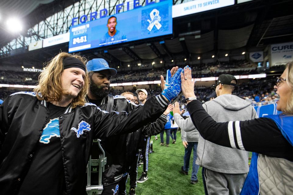 Detroit Lions drumline members Matt Quaine, left, and DeAndre Hicks high-five fans at Ford Field before the game against Chicago Bears on Sunday.