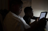 Adam Schneider, 7, center, reads on a tablet computer with his older brother Isaiah, 9, in their bedroom, Wednesday, Dec. 8, 2021, in the Brooklyn borough of New York. Their mother April Schneider says she is lucky her two oldest children attend the same school and can share technology. "When one computer is down, we can us the other," said Schneider. "There needs to be more computers. More staff. More outreach." (AP Photo/John Minchillo)