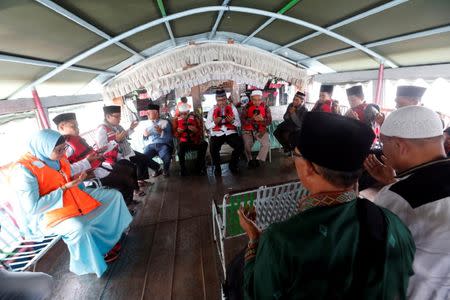 Villagers and Muslim clerics sit on a boat as they pray for the missing passengers, after a ferry sank earlier this week in Lake Toba in Simalungun, North Sumatra, Indonesia, June 22, 2018. REUTERS/Beawiharta