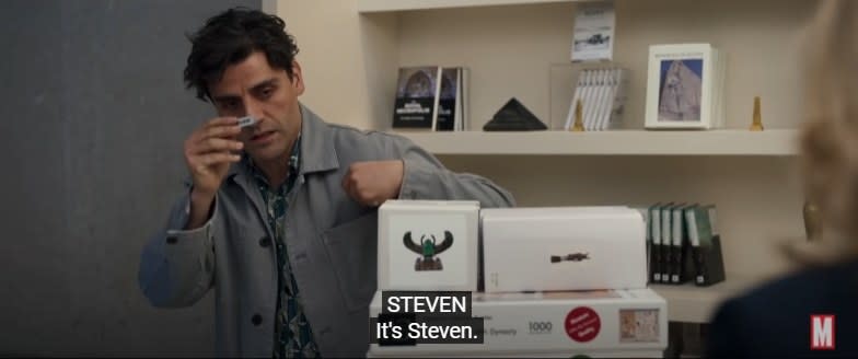 Steven holding up a name tag in a gift shop, with a subtitle reading "It's Steven"