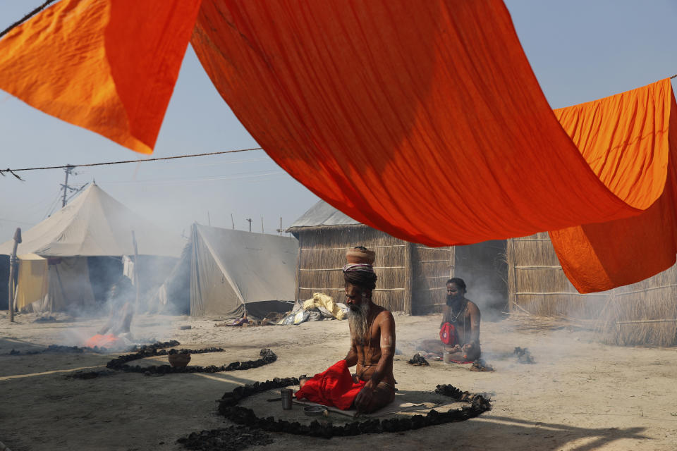 Hindu Holy men pray on the banks of the river Ganges during Magh Mela festival, in Prayagraj, India. Tuesday, Feb. 16, 2021. Millions of people have joined a 45-day long Hindu bathing festival in this northern Indian city, where devotees take a holy dip at Sangam, the sacred confluence of the rivers Ganga, Yamuna and the mythical Saraswati. Here, they bathe on certain days considered to be auspicious in the belief that they be cleansed of all sins. (AP Photo/Rajesh Kumar Singh)