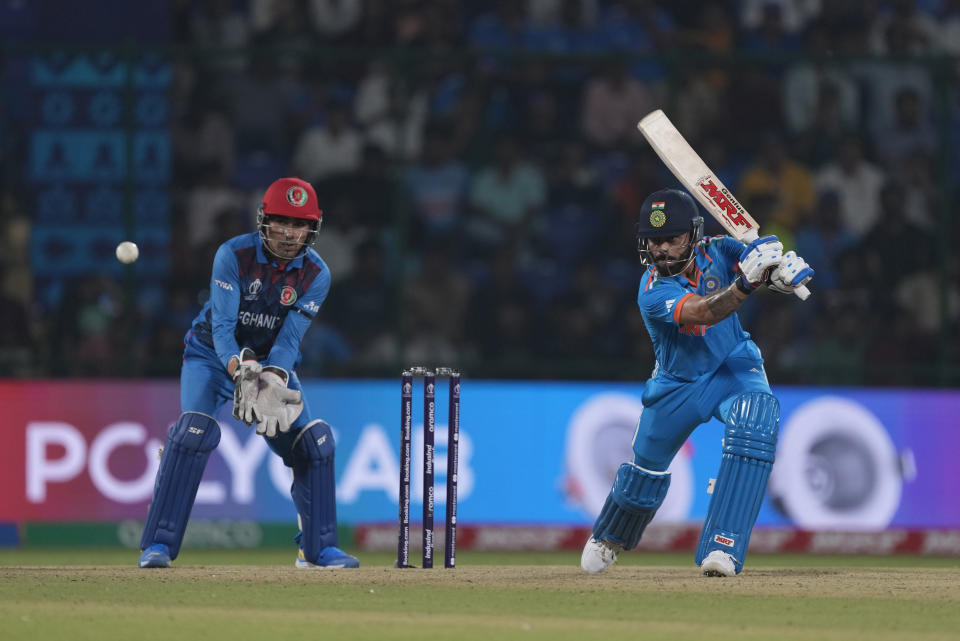 India's Virat Kohli plays a shot as Afghanistan's Rahmanullah Gurbaz watches during the ICC Men's Cricket World Cup match between Afghanistan and India in New Delhi, India, Wednesday, Oct. 11, 2023. (AP Photo/Manish Swarup)